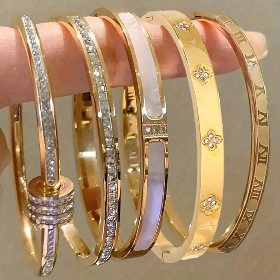 Set of gold bangles with different designs on a neutral background