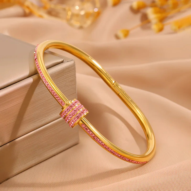 Gold bracelet with pink stones on a beige fabric background