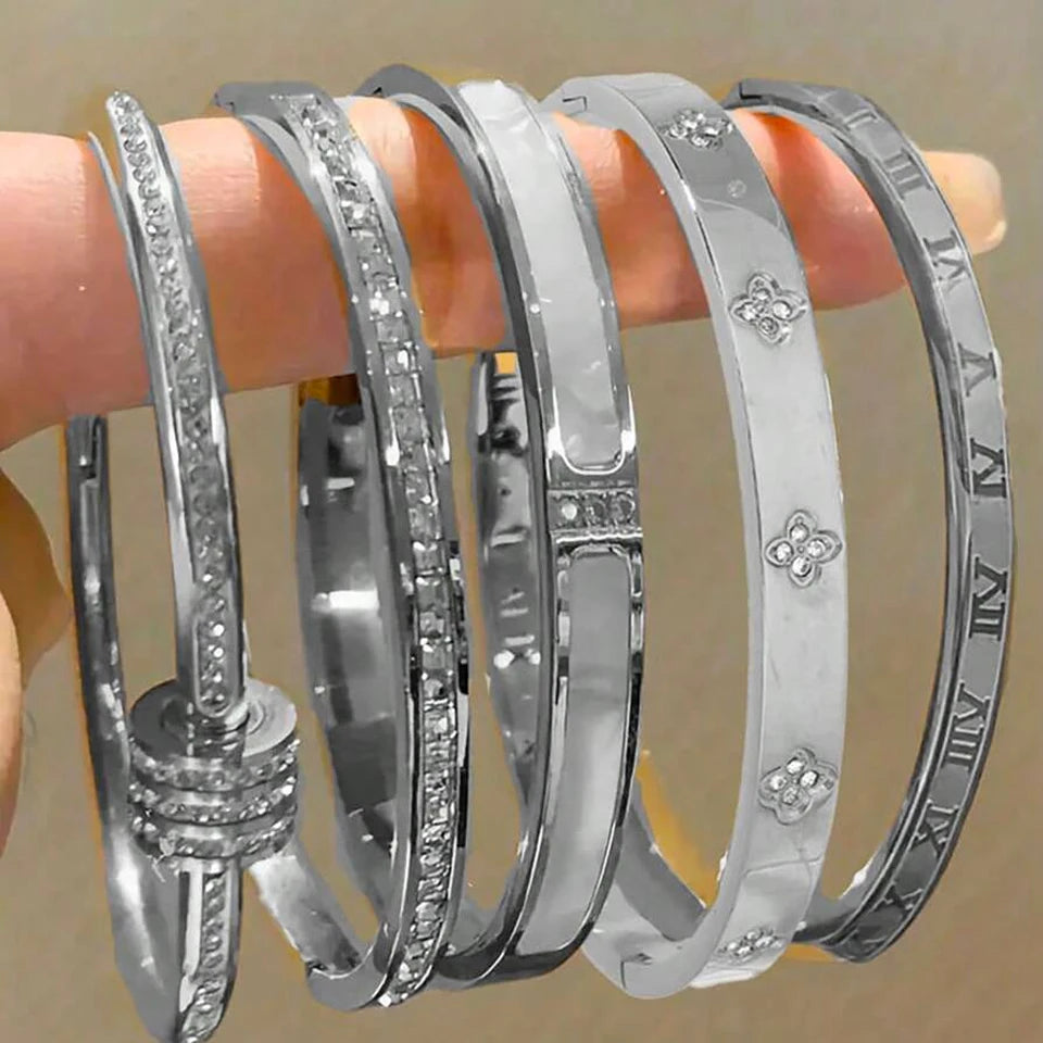 Set of silver bangles with floral and Roman numeral designs on a wooden stick.