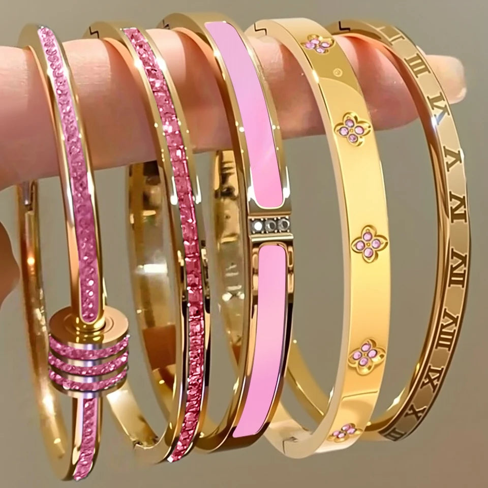 Gold and pink bangles on a hand against a neutral background