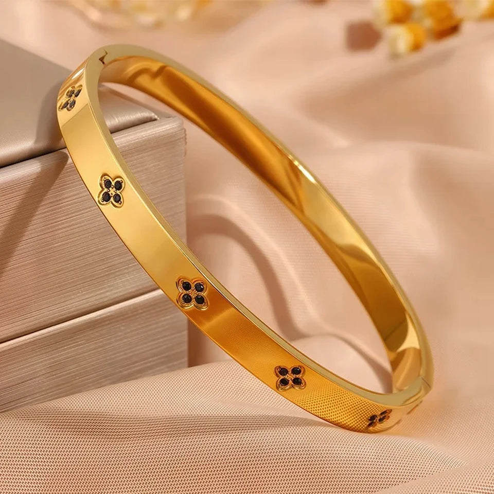 Gold bracelet with floral designs on a beige fabric background