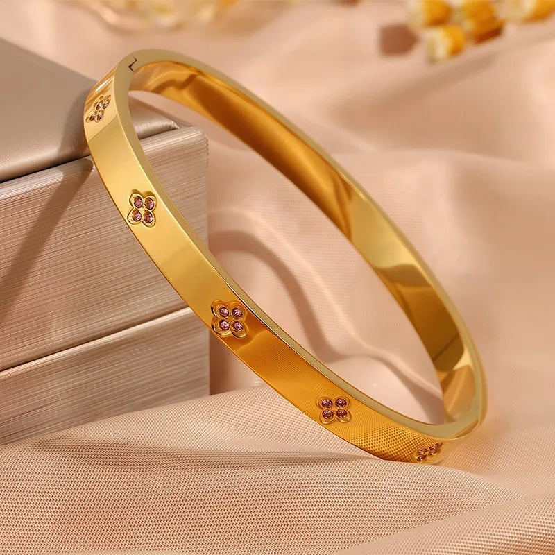 Gold bracelet with floral designs on a beige fabric background