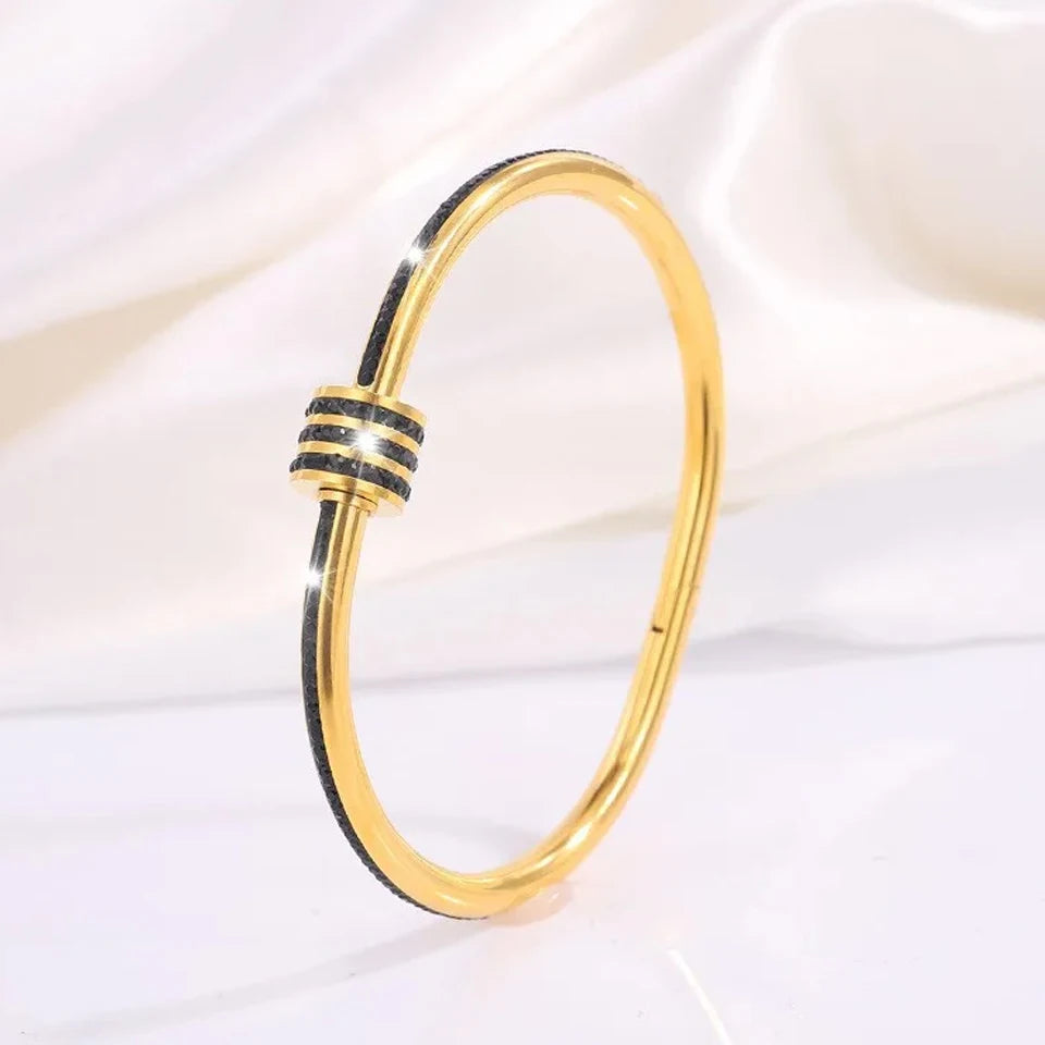 Gold bracelet with black accents on a white background