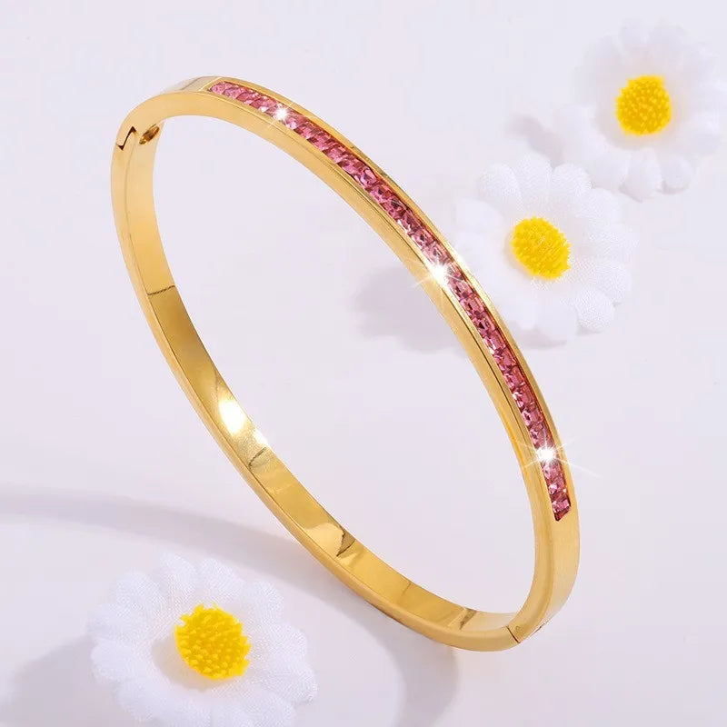 Gold bracelet with pink stones on a white background with yellow flowers